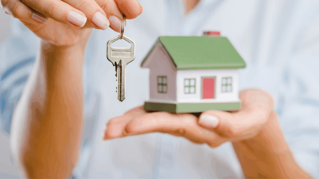 Femme qui tient dans l'une de ses mains une maison miniature et une clé dans l'autre