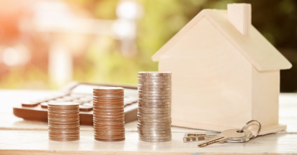 Une maison accompagnée d’une calculatrice, de pièces de monnaie et d’un trousseau de clés