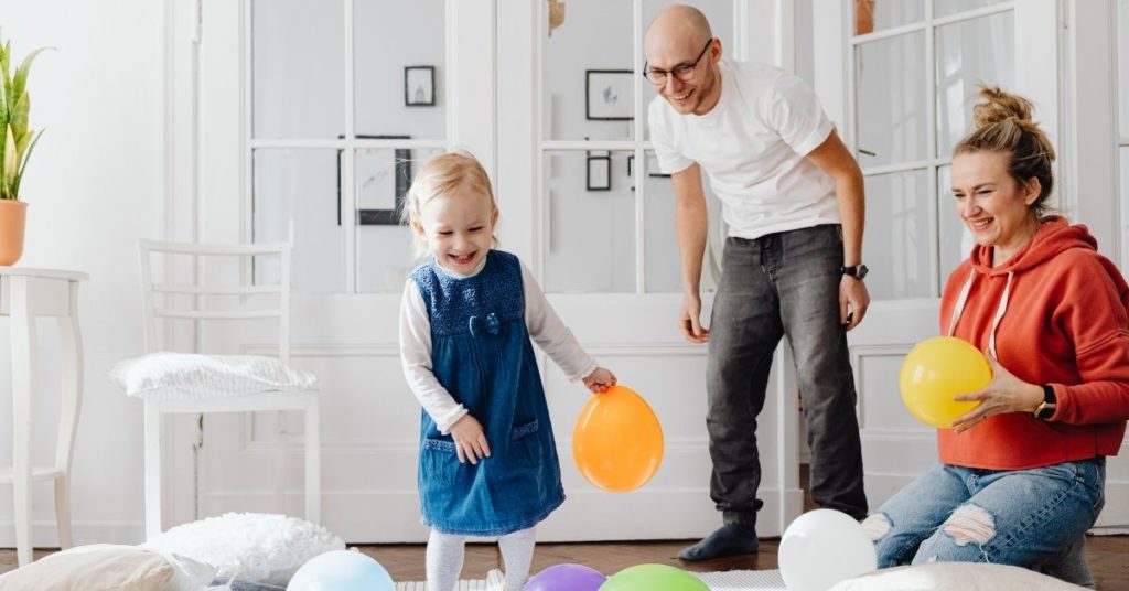 Scène familiale : un couple et leur enfant jouant avec des ballons de baudruche à la maison