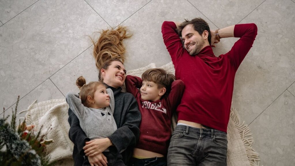 Couple avec 2 enfants allongés sur le sol de leur maison