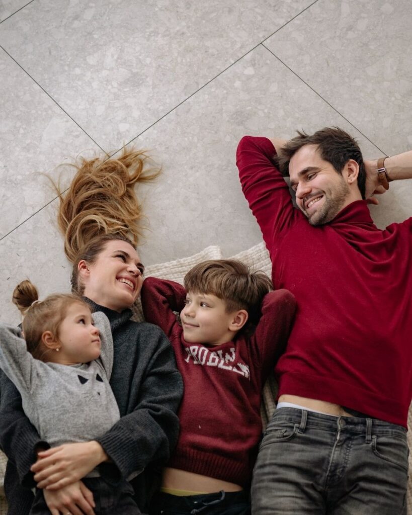 Couple avec 2 enfants allongés sur le sol de leur maison