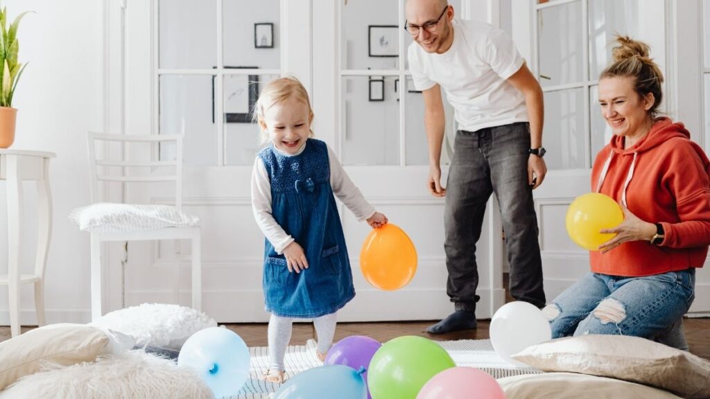 Scène familiale : un couple et leur enfant jouant avec des ballons de baudruche à la maison