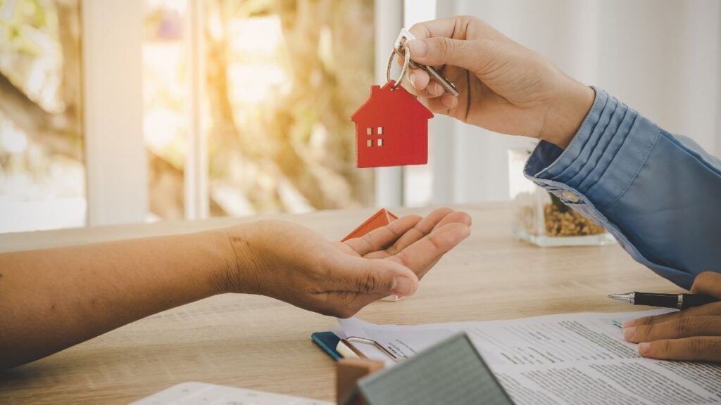 Deux personnes échangeant un trousseau de clés, dont seules les mains sont visibles