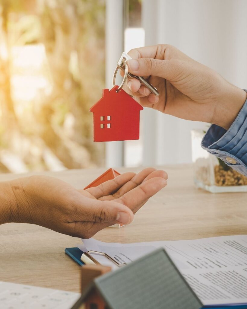 Deux personnes échangeant un trousseau de clés, dont seules les mains sont visibles