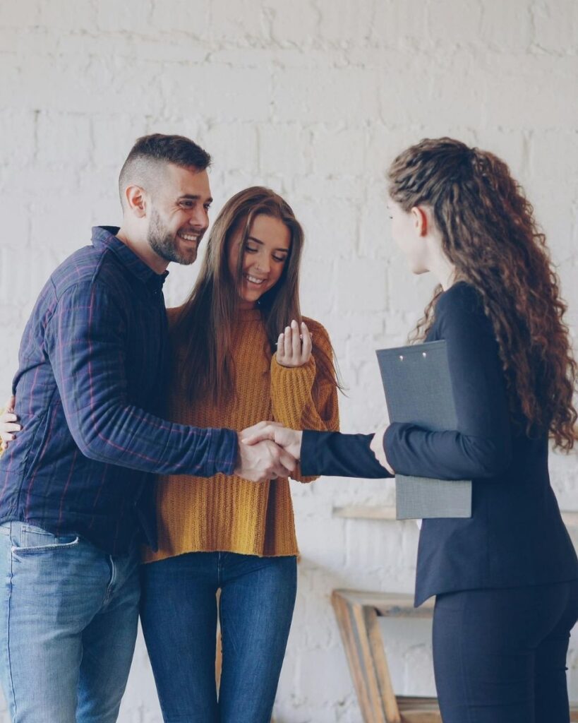 Couple recevant les clés de leur logement des mains d'une professionnelle